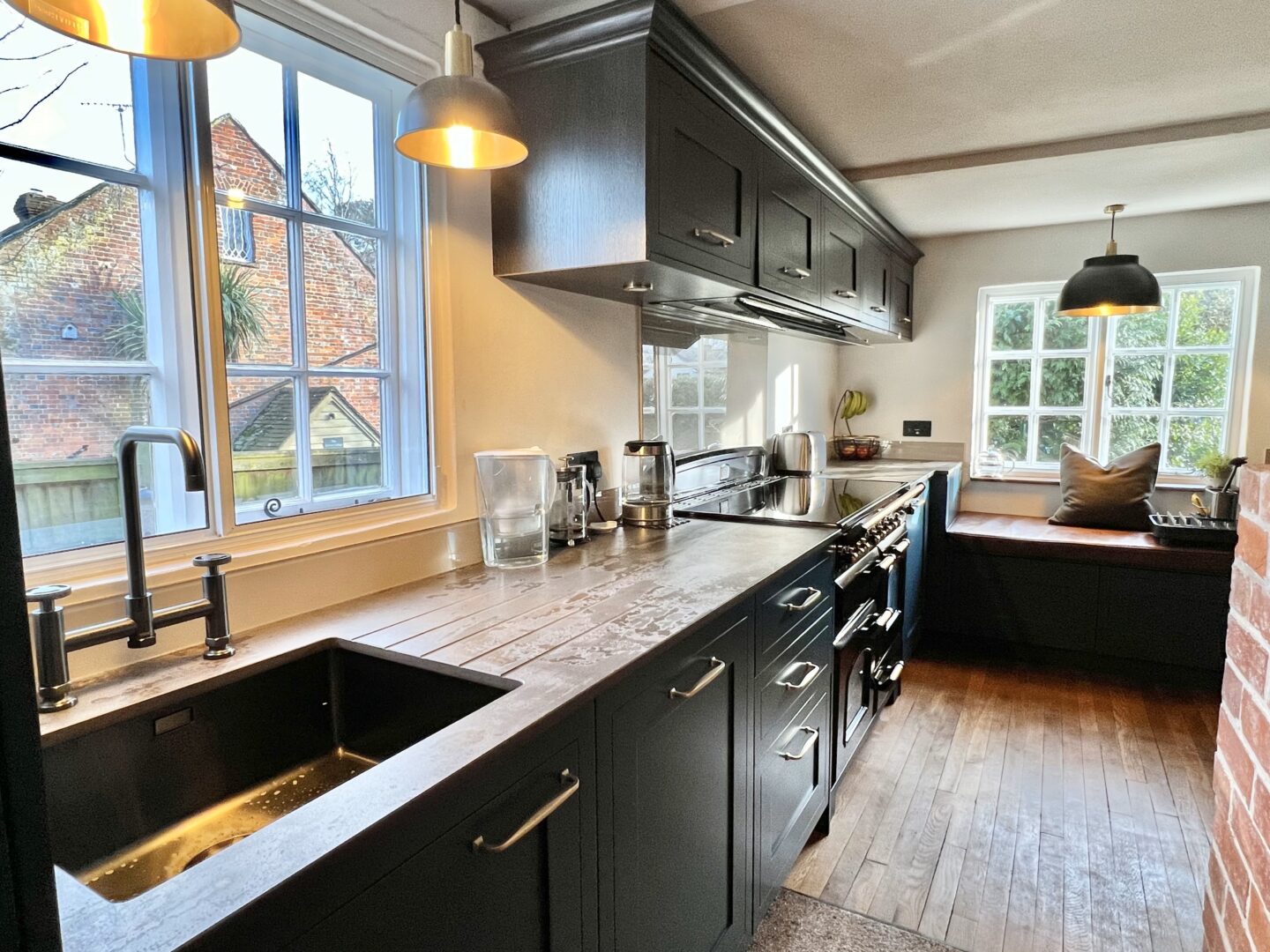 Painted Shaker kitchen with Brass handles, cornice and tall larder to house the boiler and undermounted sink in gunmetal finish with a industrial two lever tap. Dekton worktops