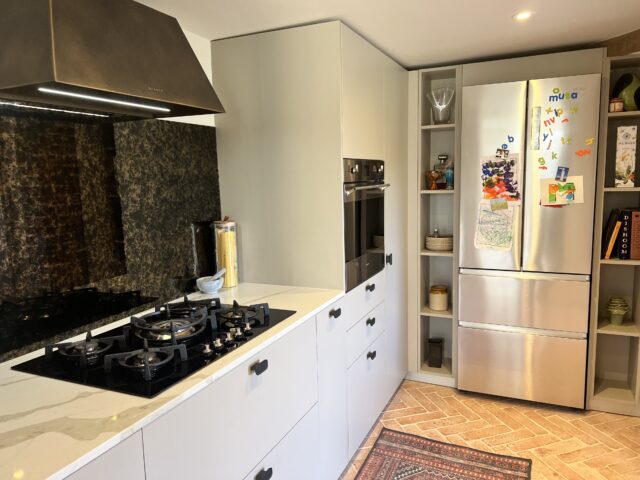 Vintage glass splash back with bronze cooker hood and a stunning gas hob